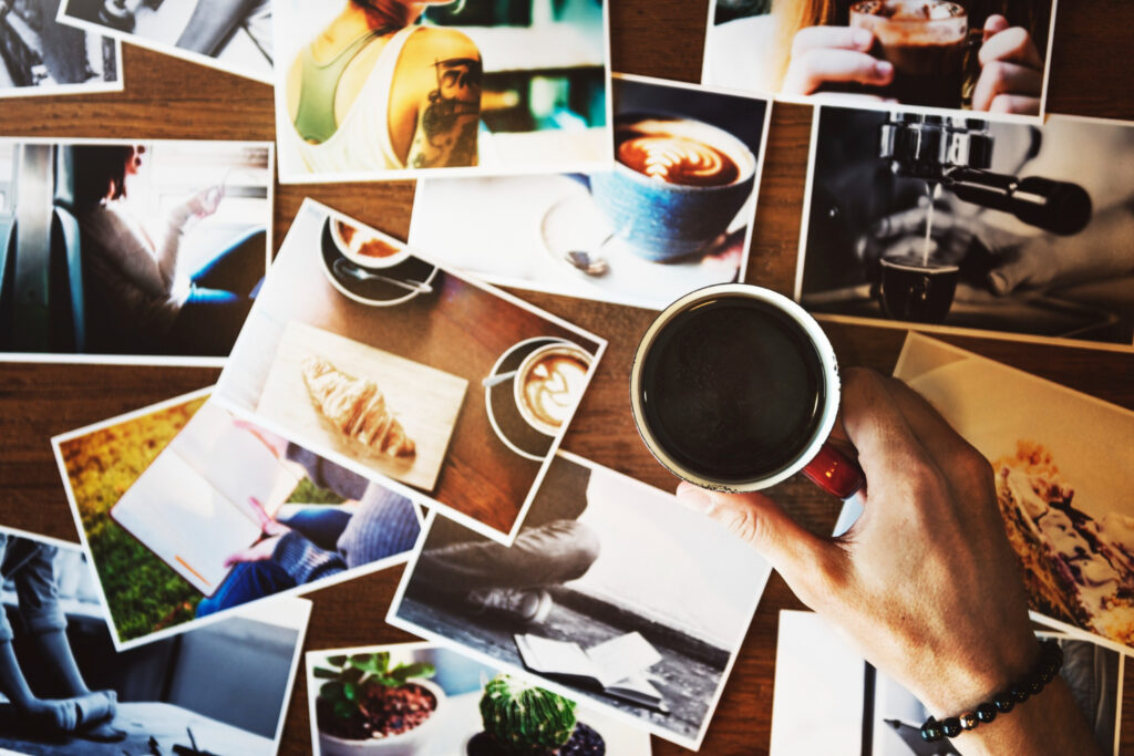 hand holding coffee cup with may photograph table